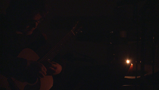 A guitarist playing by candlelight