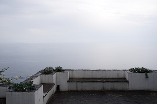 A view of the sea from a high terrace; haze blurs the boundary between sea and sky.